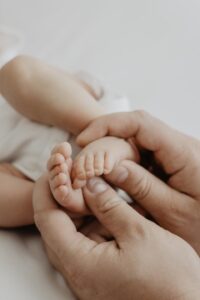 Papahände, die kleine Babyfüße halten