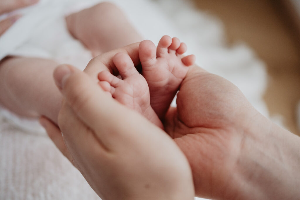 Foto von Neugeborenen-Füßchen in den Händen der Mama.