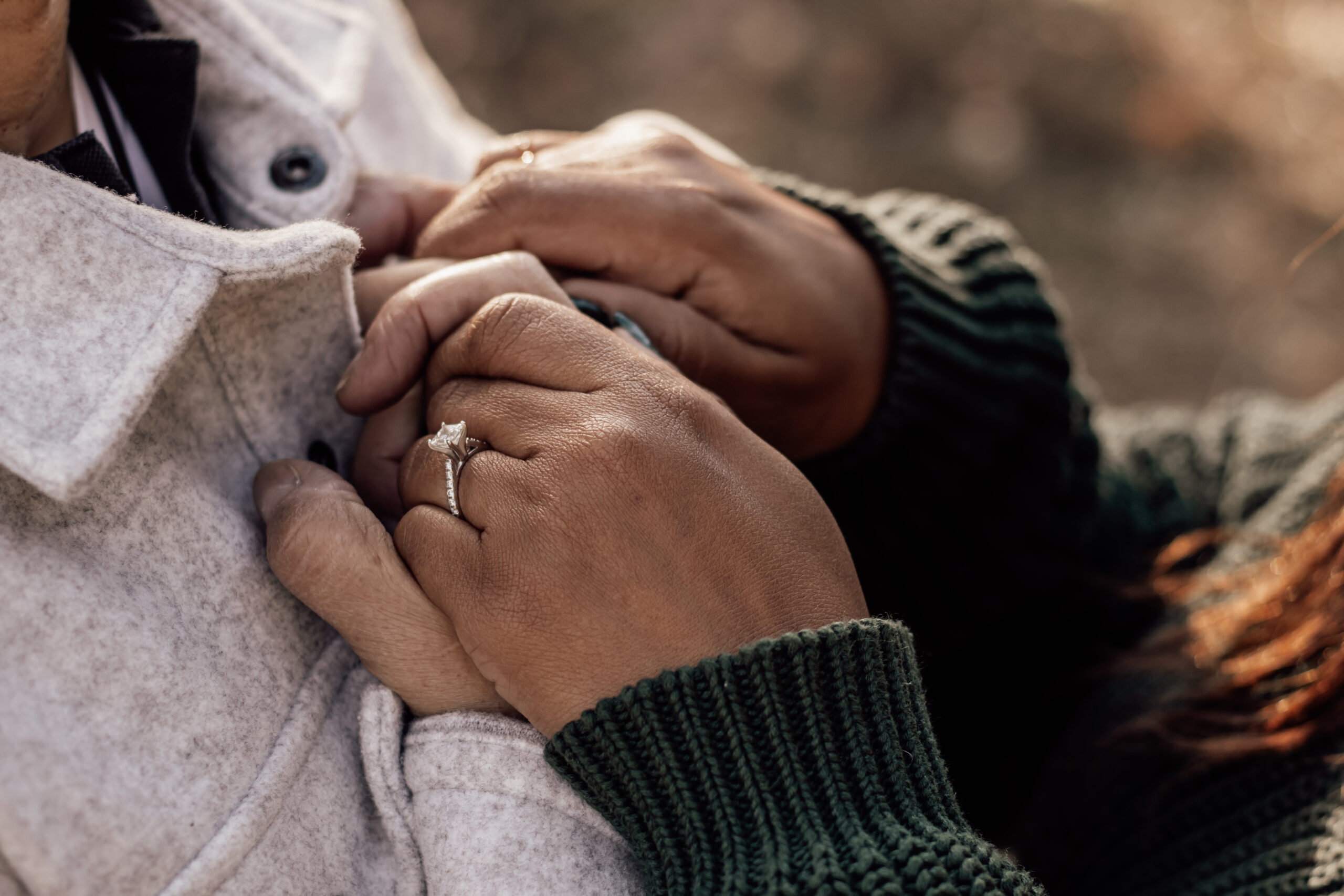Ein Foto eines Paares, das sich die Hände hält auf Höhe der Brust.